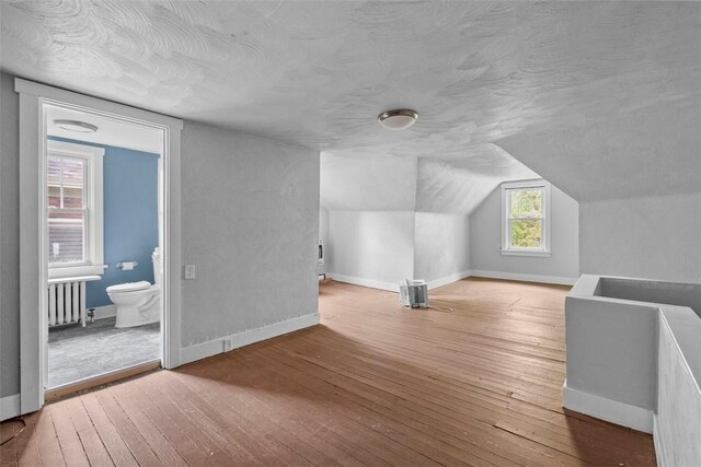 1140 N Negley Ave, Highland Park, PA 15206 - additional living space featuring hardwood / wood-style flooring, a textured ceiling, baseboards, radiator heating unit, and vaulted ceiling