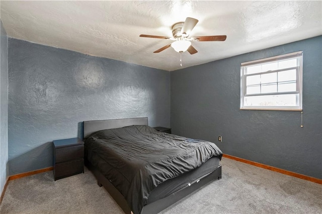 carpeted bedroom featuring a textured wall, baseboards, and ceiling fan