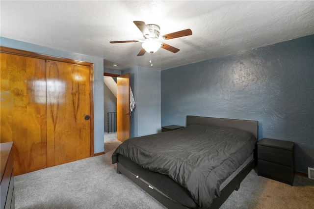 bedroom featuring a textured wall, carpet floors, a ceiling fan, and a textured ceiling