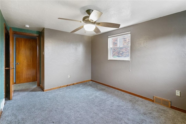 carpeted spare room with baseboards and a ceiling fan