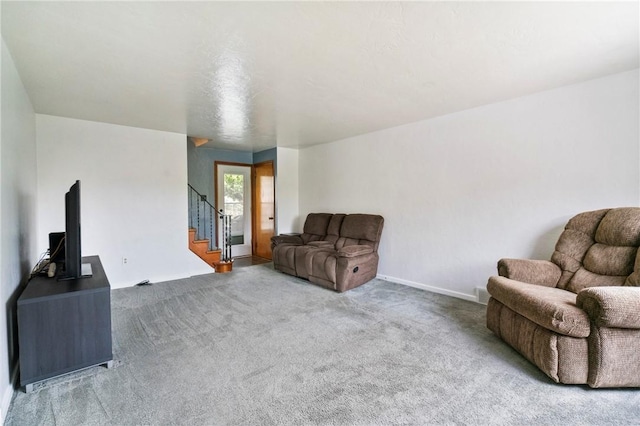 carpeted living area featuring stairway and baseboards