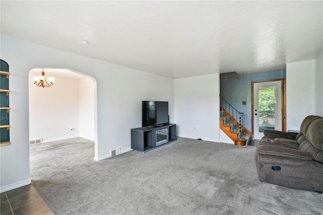 living area featuring arched walkways, a chandelier, carpet, stairs, and baseboards
