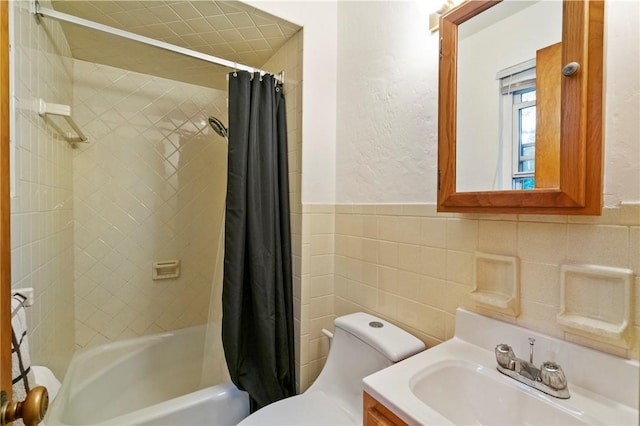 bathroom featuring toilet, shower / bath combo with shower curtain, tile walls, vanity, and a wainscoted wall