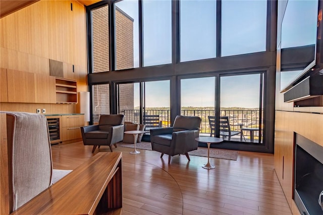 living room with beverage cooler, wood finished floors, and a towering ceiling
