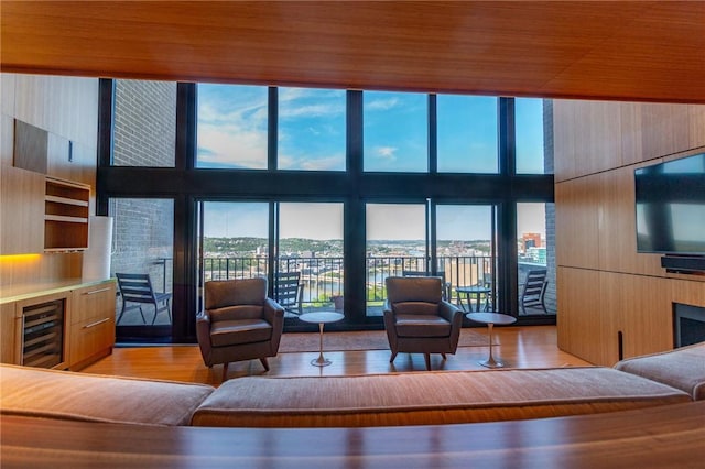 living room with wine cooler, a towering ceiling, and wood finished floors