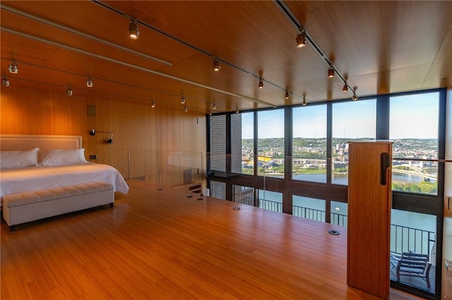 bedroom with track lighting, wood finished floors, and a wall of windows