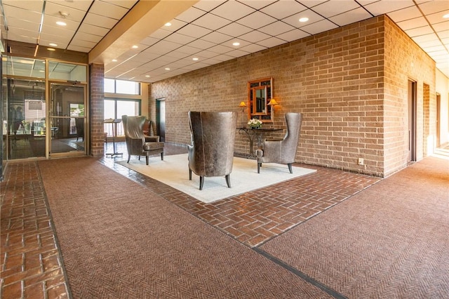 building lobby with brick wall, a drop ceiling, and recessed lighting