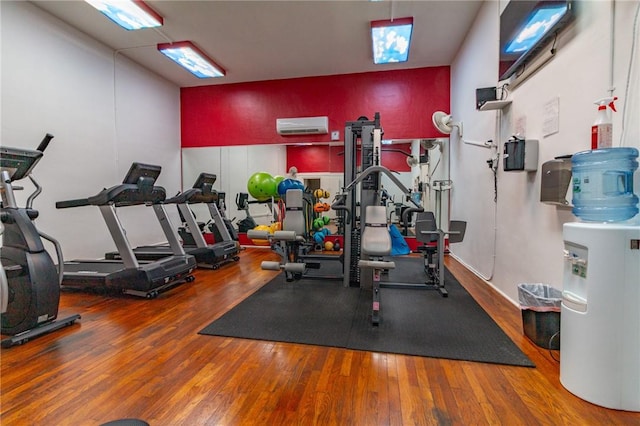 workout area with wood-type flooring and a wall mounted AC