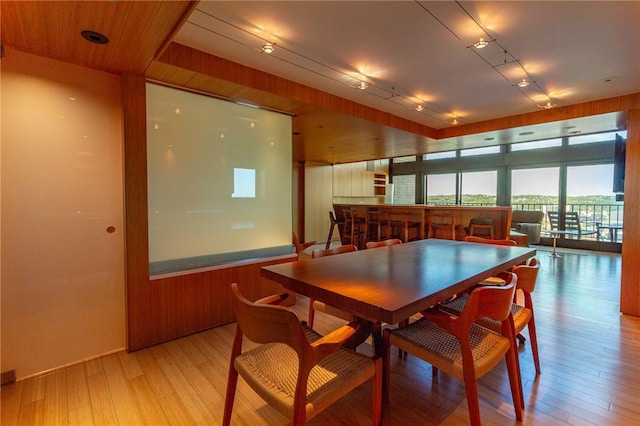 dining area with light wood finished floors and a bar