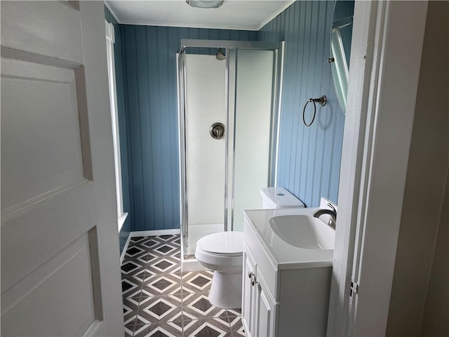 bathroom with a shower stall, vanity, toilet, ornamental molding, and a decorative wall