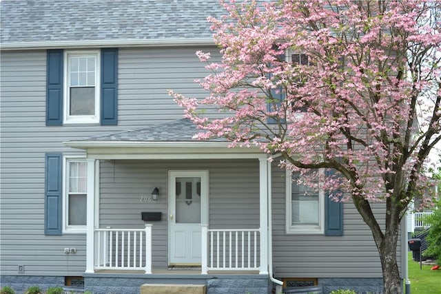view of front facade with a shingled roof and covered porch