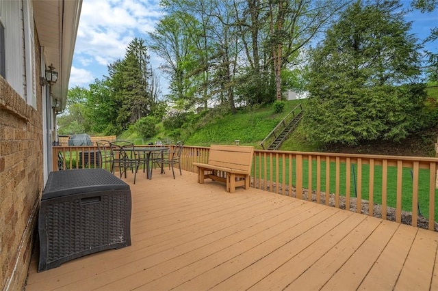 deck with outdoor dining space and a yard