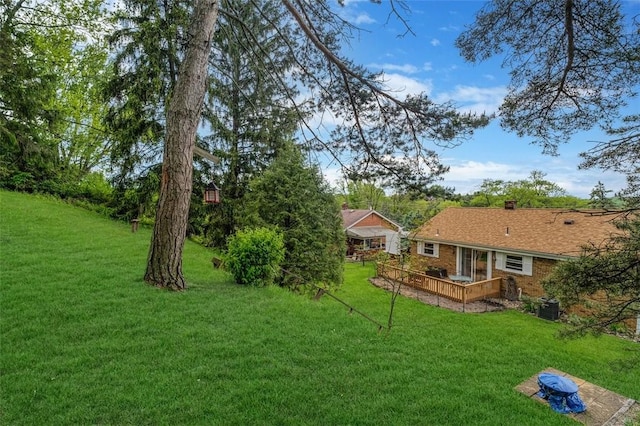 view of green lawn featuring central air condition unit and a deck