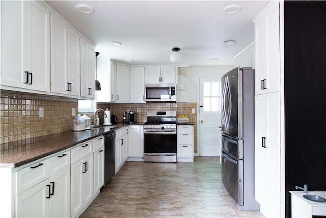 kitchen with appliances with stainless steel finishes, open shelves, a sink, tasteful backsplash, and white cabinetry