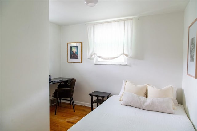 bedroom featuring wood finished floors, a desk, and baseboards
