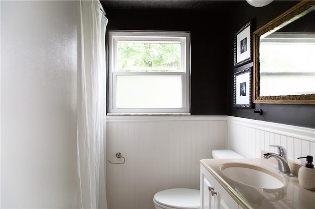 full bathroom with a wainscoted wall, toilet, vanity, and a shower with curtain