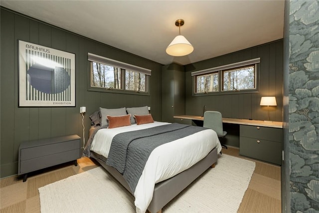 bedroom featuring multiple windows and a decorative wall