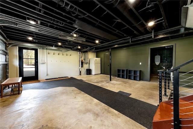 basement featuring freestanding refrigerator, electric panel, and stairway