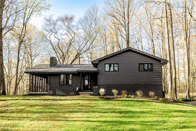 split level home featuring brick siding, a chimney, and a front yard