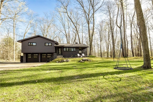 rear view of house with an attached garage, driveway, and a lawn