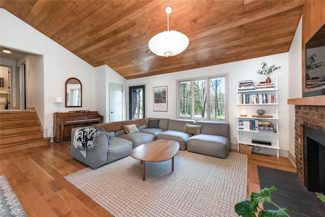 living area with lofted ceiling, wood ceiling, a fireplace, wood finished floors, and stairway