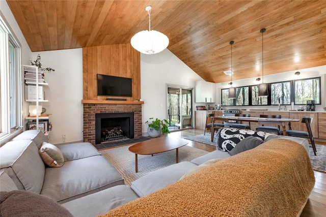 living area featuring wooden ceiling, wood finished floors, high vaulted ceiling, and a brick fireplace