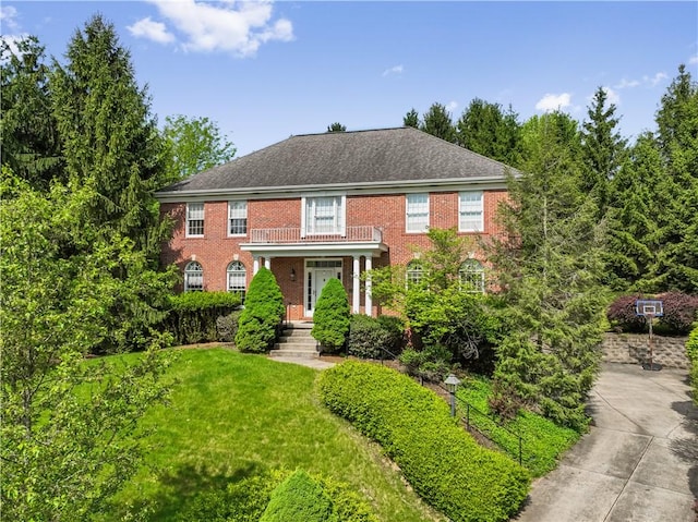 georgian-style home featuring brick siding, a front yard, and concrete driveway