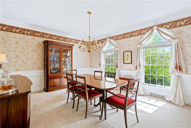 dining space featuring a chandelier, wainscoting, wallpapered walls, and light colored carpet
