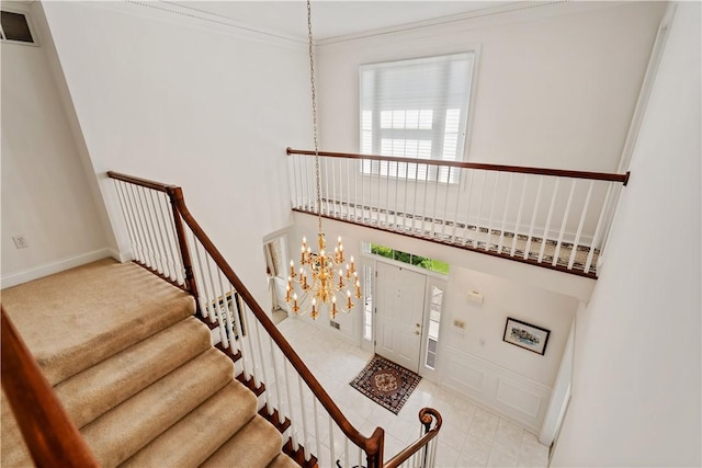 entrance foyer featuring a chandelier, healthy amount of natural light, stairs, and crown molding