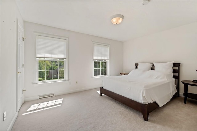 carpeted bedroom featuring multiple windows and baseboards