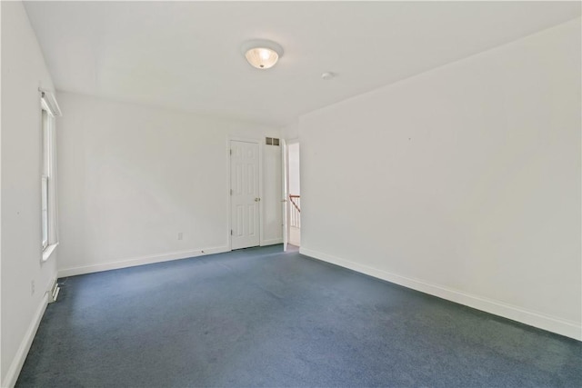 unfurnished room with baseboards and dark carpet