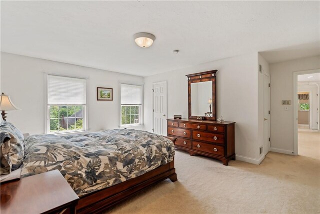 bedroom with light colored carpet and baseboards