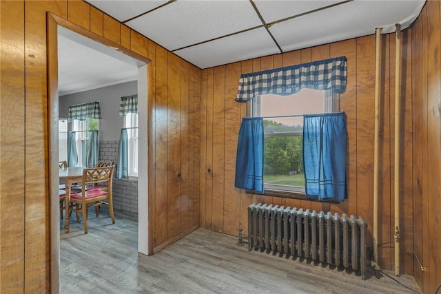 empty room with radiator heating unit, wood finished floors, and wooden walls
