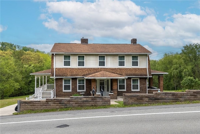 view of front of property with a chimney, covered porch, and brick siding