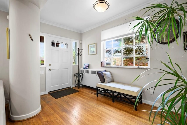 foyer entrance with radiator, wood-type flooring, crown molding, and baseboards