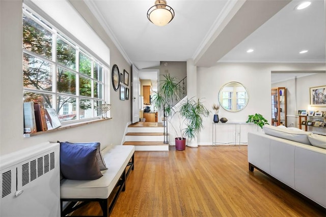 foyer entrance featuring radiator heating unit, wood finished floors, recessed lighting, ornamental molding, and stairs