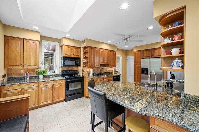 kitchen featuring open shelves, black appliances, a sink, a breakfast bar, and a ceiling fan