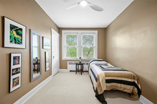 bedroom with radiator heating unit, baseboards, light colored carpet, and a ceiling fan