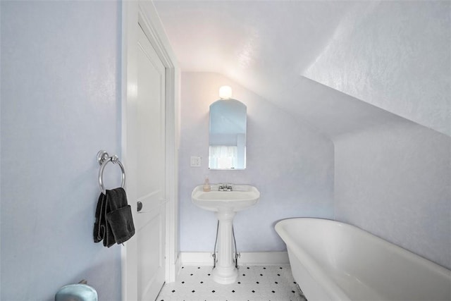 bathroom with vaulted ceiling, a freestanding tub, baseboards, and tile patterned floors