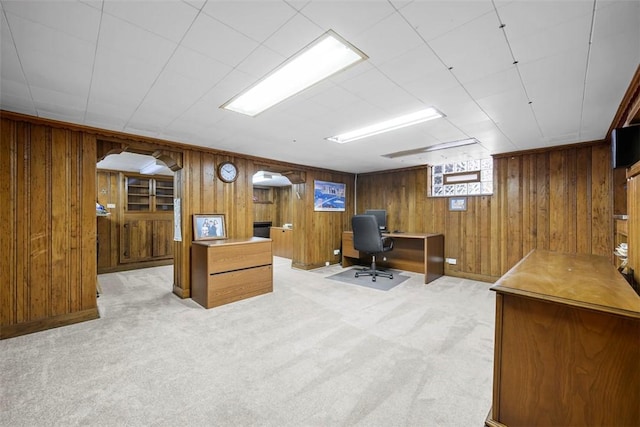 office area featuring light carpet and wood walls