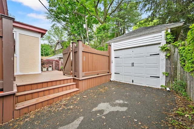 detached garage featuring driveway and fence