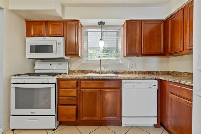 kitchen featuring white appliances, a sink, light tile patterned floors, and brown cabinetry
