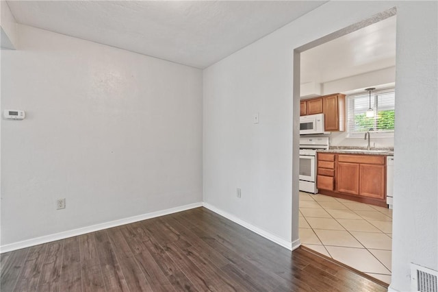 unfurnished room featuring a sink, light wood-style floors, and baseboards