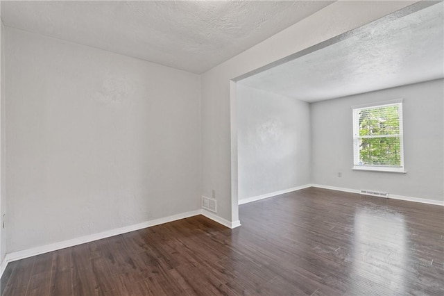 empty room with wood finished floors, a textured ceiling, and baseboards