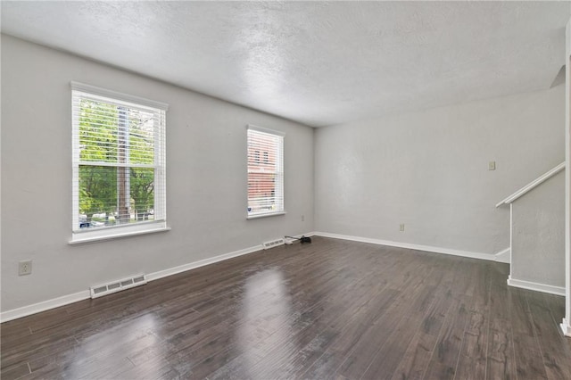 unfurnished living room featuring dark wood-style flooring, baseboards, and a textured ceiling