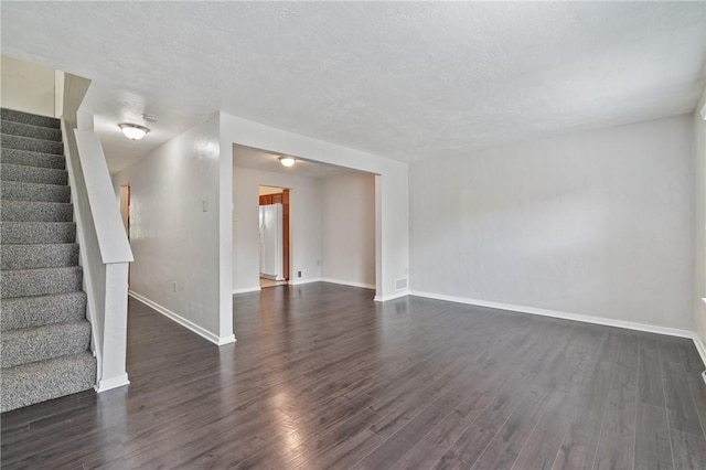 unfurnished living room featuring dark wood-type flooring, stairway, and baseboards