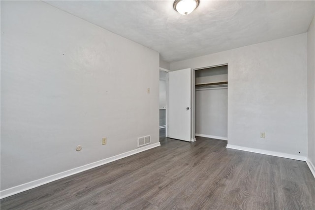 unfurnished bedroom with dark wood-style floors, baseboards, and a closet