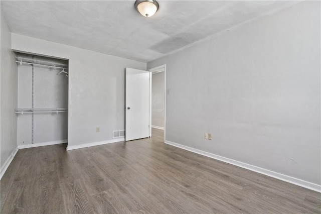 unfurnished bedroom featuring wood finished floors, a closet, and baseboards