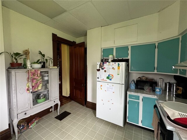 816 Main St, Brockway, PA 15824 - kitchen with freestanding refrigerator, a drop ceiling, light tile patterned flooring, light countertops, and green cabinets