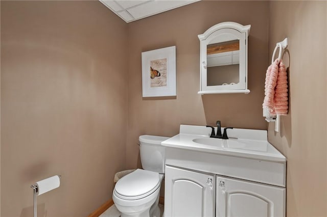 half bathroom featuring toilet, vanity, and baseboards